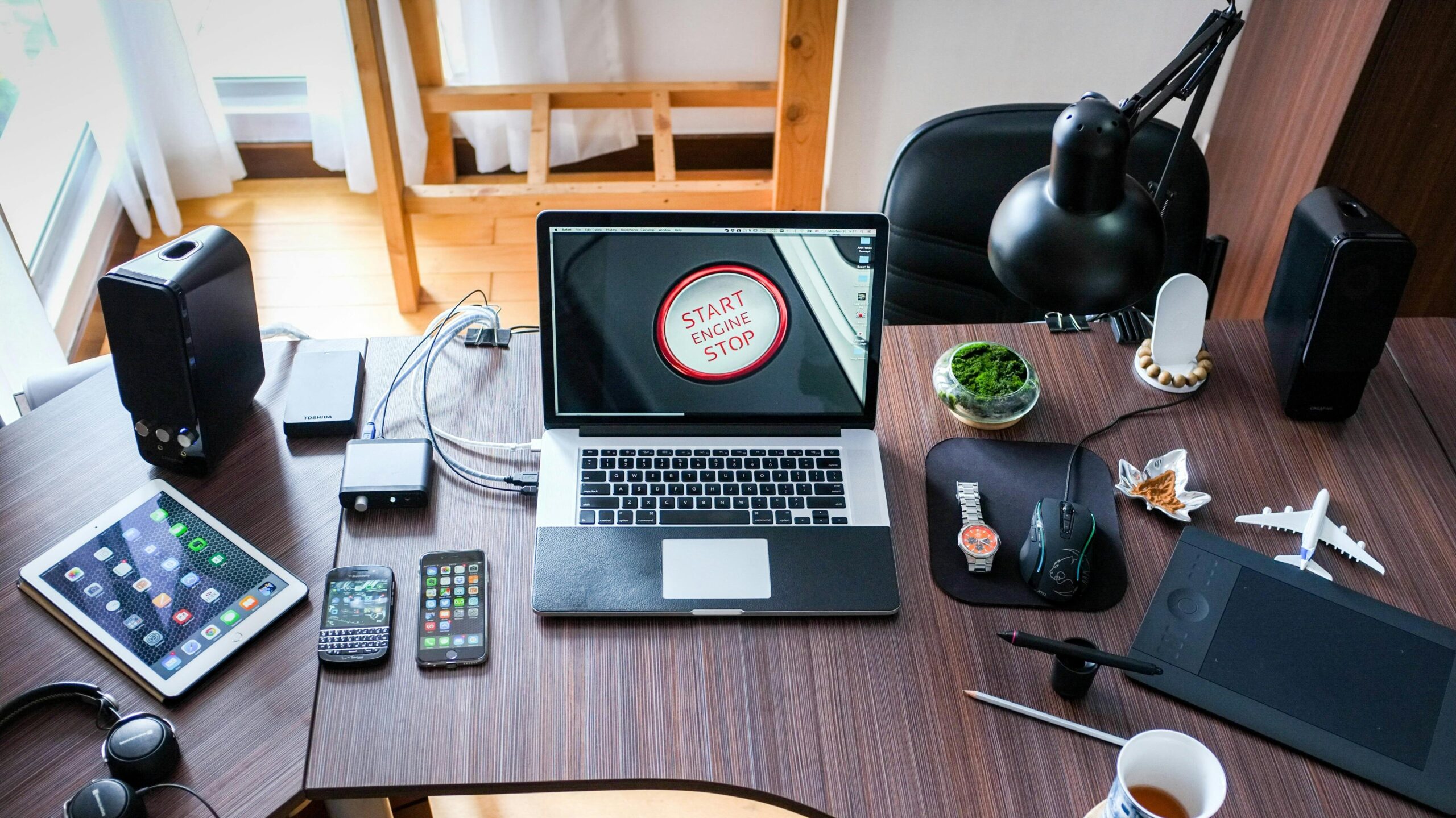 A contemporary office desk setup with laptops, gadgets, and accessories, creating a tech-savvy workplace.